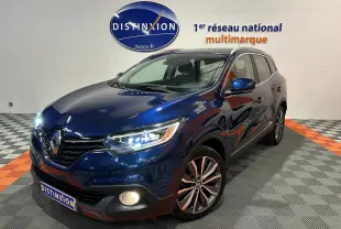 Renault Kadjar TCe 130 Intens bleu en 3/4 avant droit avec phares allumés dans showroom multimarque.