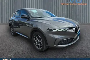 Vue 3/4 avant d'une Alfa Romeo Tonale gris métallisé avec jantes alliage 18 pouces et phares LED allumés.