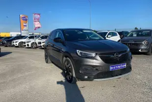 Opel Grandland X Hybrid4 2021 en pierre de lune métal, vue 3/4 avant avec calandre noire et phares LED allumés.