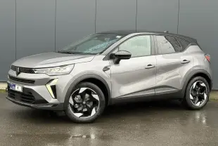 Renault Captur 2025 gris Cassiopée avec toit noir, vue 3/4 avant droit sur sol humide, jantes noires distinctives.