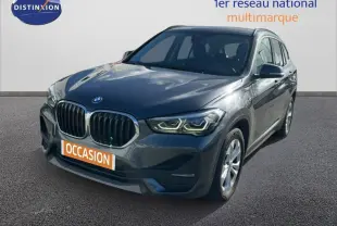BMW X1 gris foncé vue 3/4 avant droit, avec calandre double haricot et phares LED allumés.