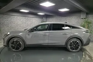 Profil droit de la Peugeot 408 gris métallisé avec jantes alliage noires et toit noir dans un showroom.