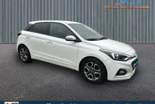 Hyundai i20 blanc vue 3/4 avant droit, jantes alliage 16 pouces et phares antibrouillard visibles