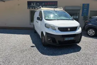 Peugeot Expert Fourgon blanc en 3/4 avant droit avec galerie de toit, stationné devant un bâtiment commercial.