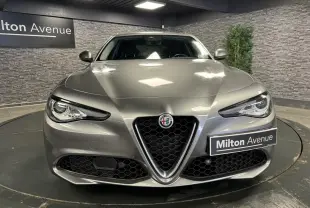 Vue frontale d'une Alfa Romeo Giulia gris métallisé avec calandre emblématique en V et phares LED distinctifs.