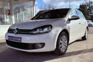 Volkswagen Golf blanc vue 3/4 avant droit avec phares allumés et jantes alliage en extérieur.