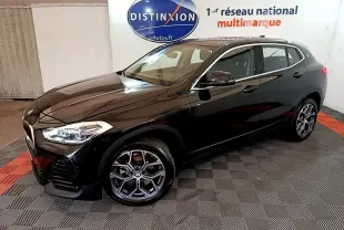 BMW X2 sDrive18i Lounge noire vue 3/4 avant droit dans un showroom avec jantes alliage distinctives.