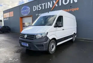 Volkswagen Crafter fourgon blanc vu en 3/4 avant droit devant un bâtiment gris avec logo Distinxion.