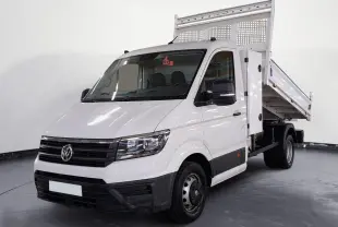Vue 3/4 avant d’un Volkswagen Crafter blanc avec benne relevée, coffre latéral et roues jumelées arrière.